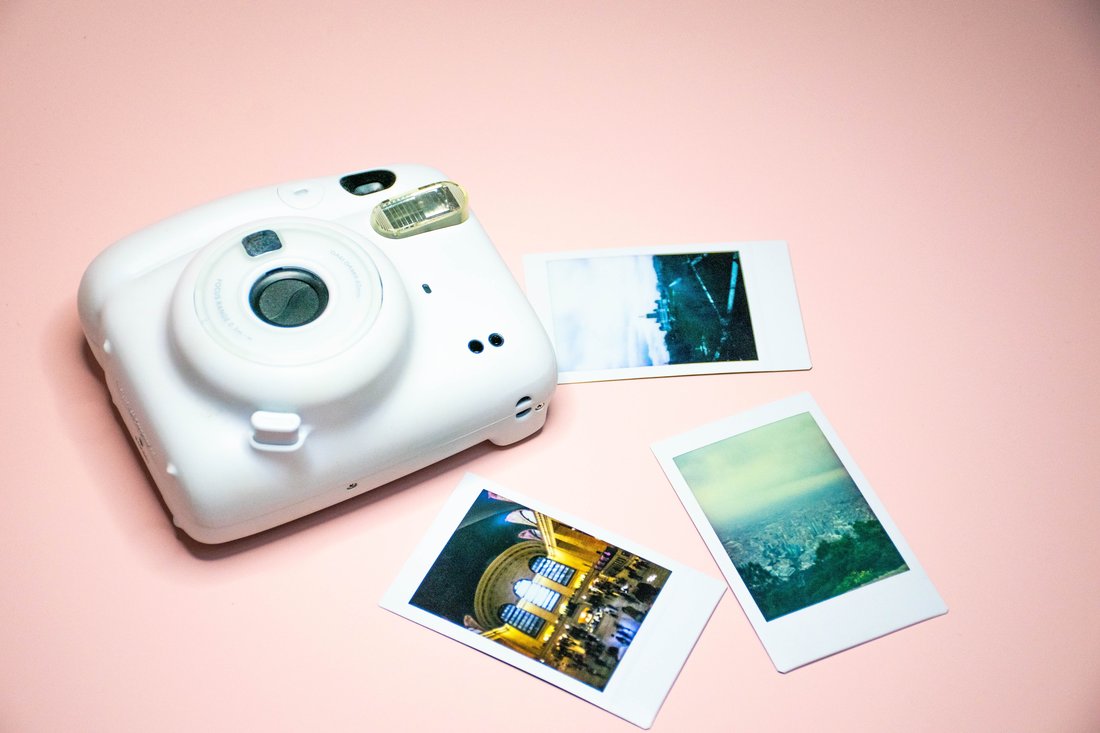 Cámara instantánea junto a fotos impresas de viaje sobre fondo de color