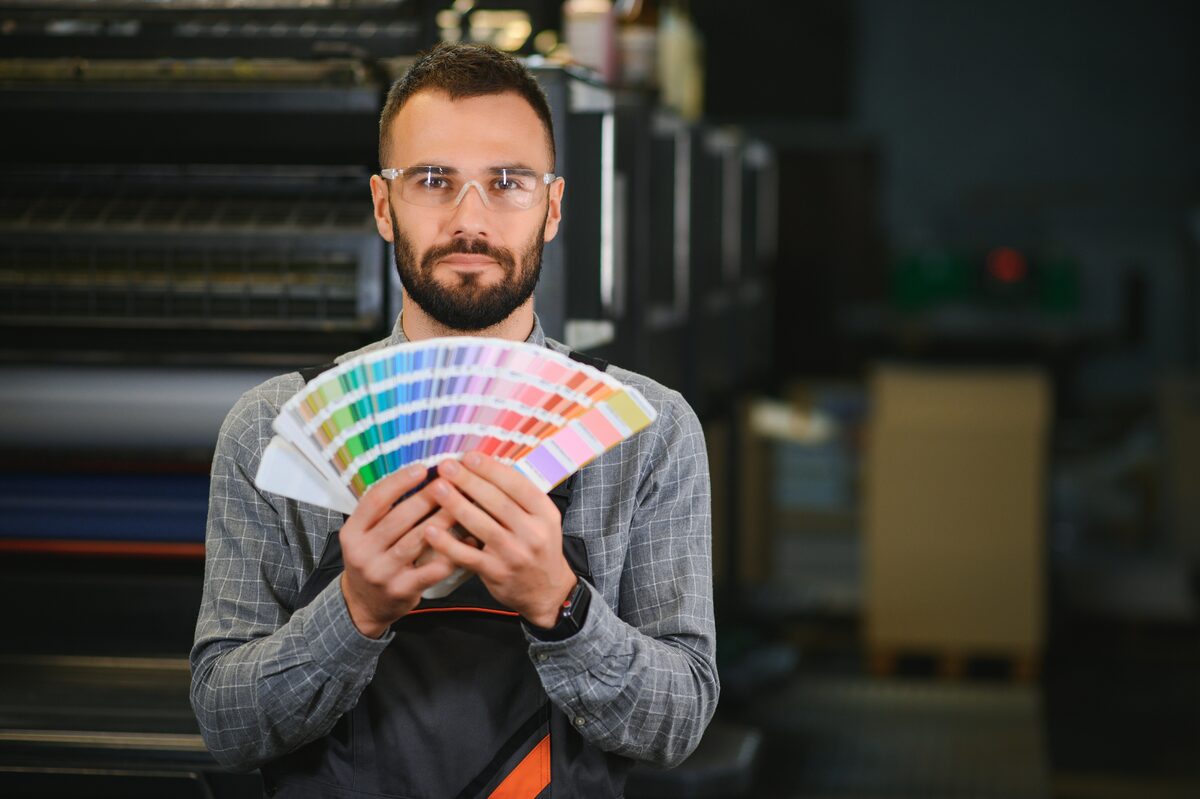Tipógrafo revisando muestras de color CMYK en imprenta profesional