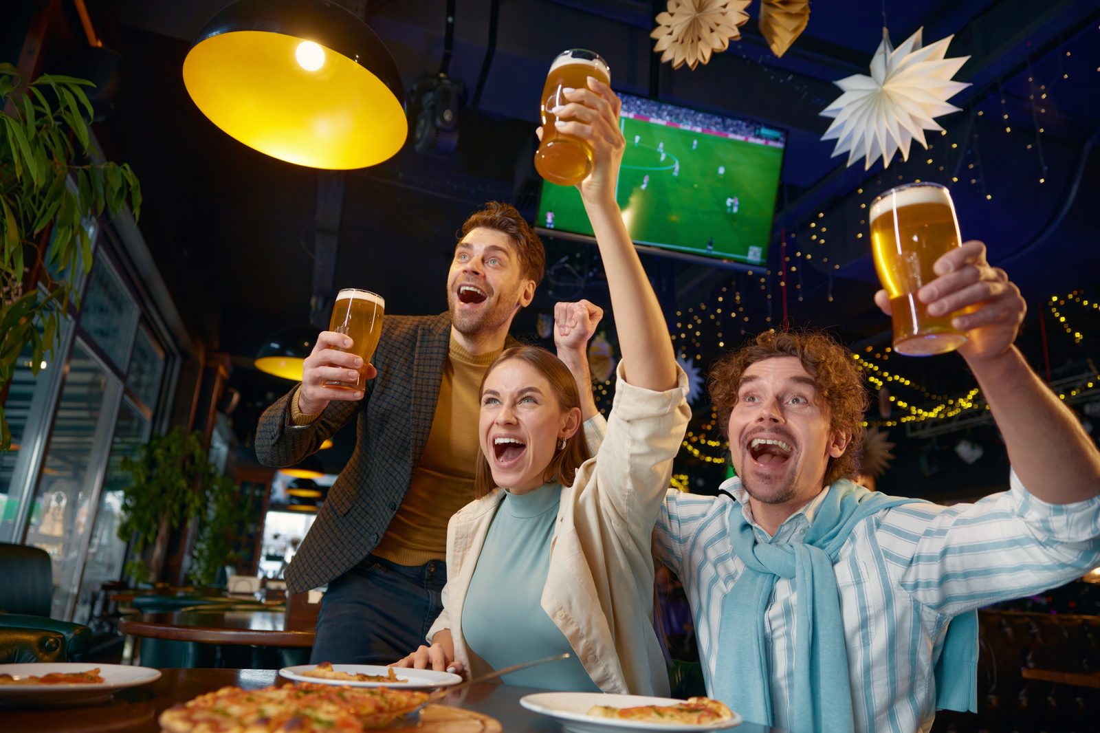 Amigos celebrando un gol del Mundial 2026 con cervezas en un bar